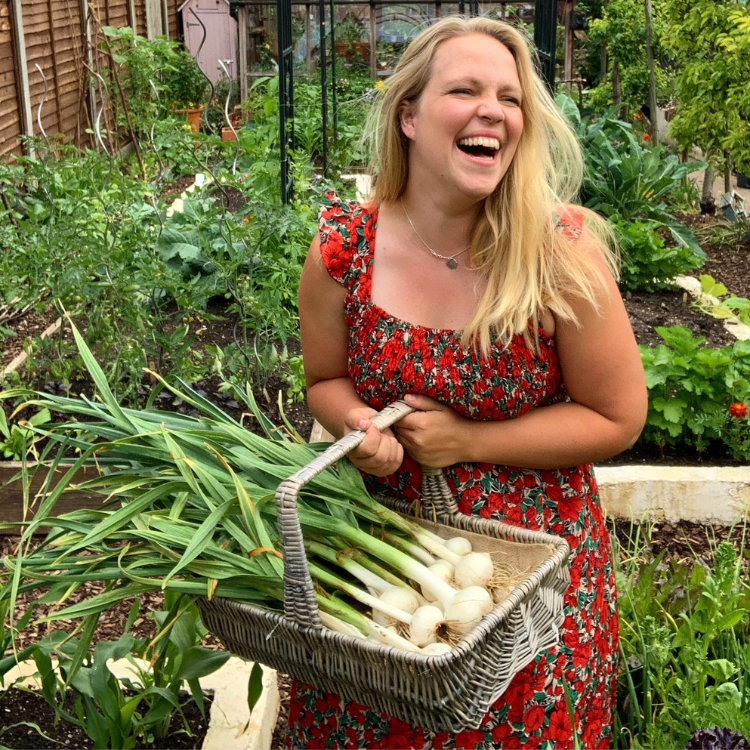 Untitled design – 2023-05-19T131508.435 Becky Searle laughing, with a wicker basket of onions